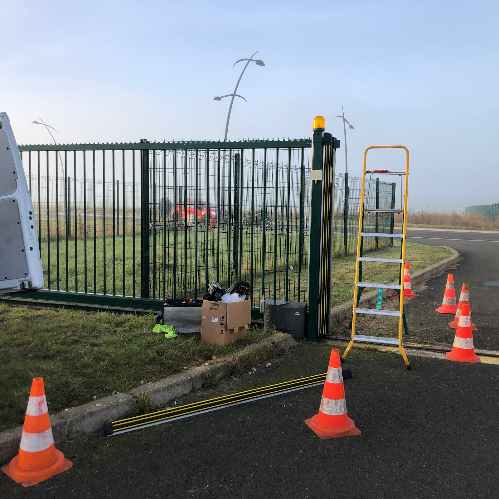 Chantier de motorisation de portail, balisé avec cônes et échelle